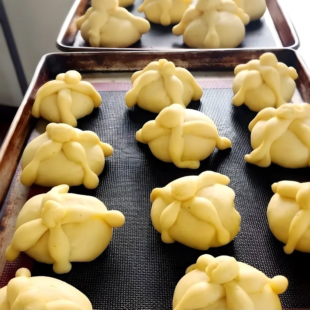 Imagen de panes de muerto recién formados en una clase artesanal de panadería.