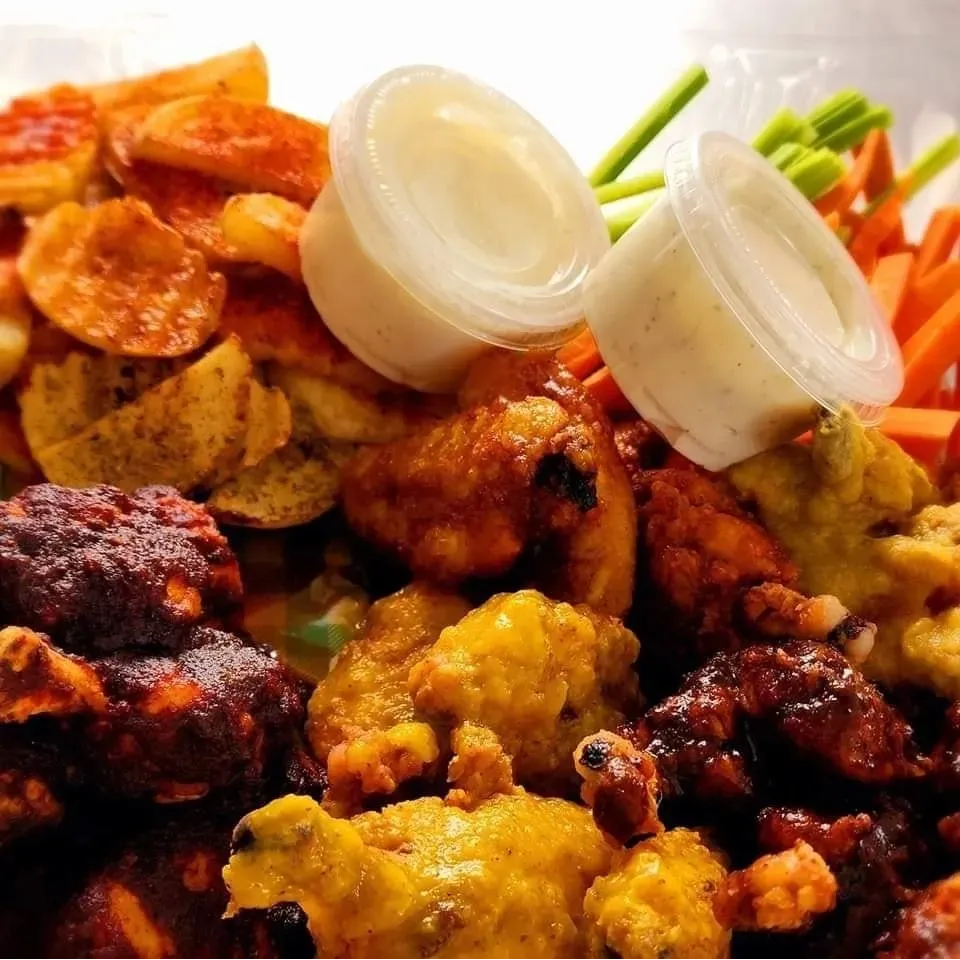 Variedad de alitas de pollo con aderezos, perfectas para compartir.