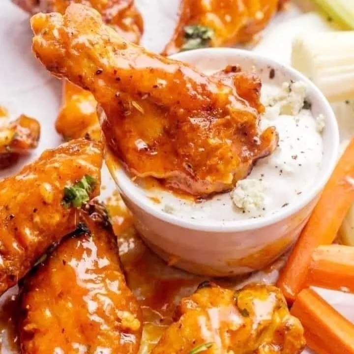 Imagen de alitas de pollo fritas con salsa picante y aderezo de queso azul.