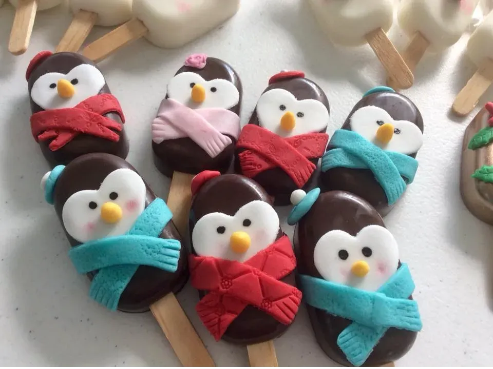 Paletas de pingüino de chocolate artesanal, decoradas con fondant.