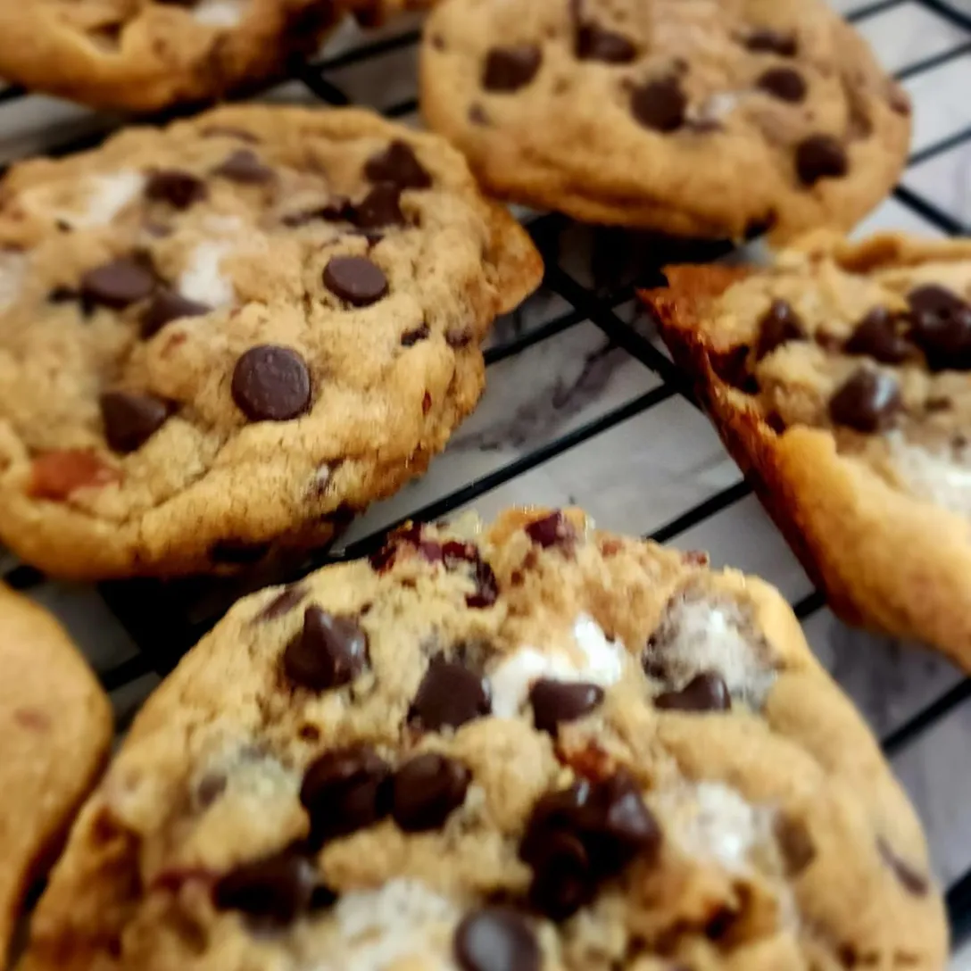 Galletas caseras con trozos de chocolate, blancas y rojas en una superficie de mármol.