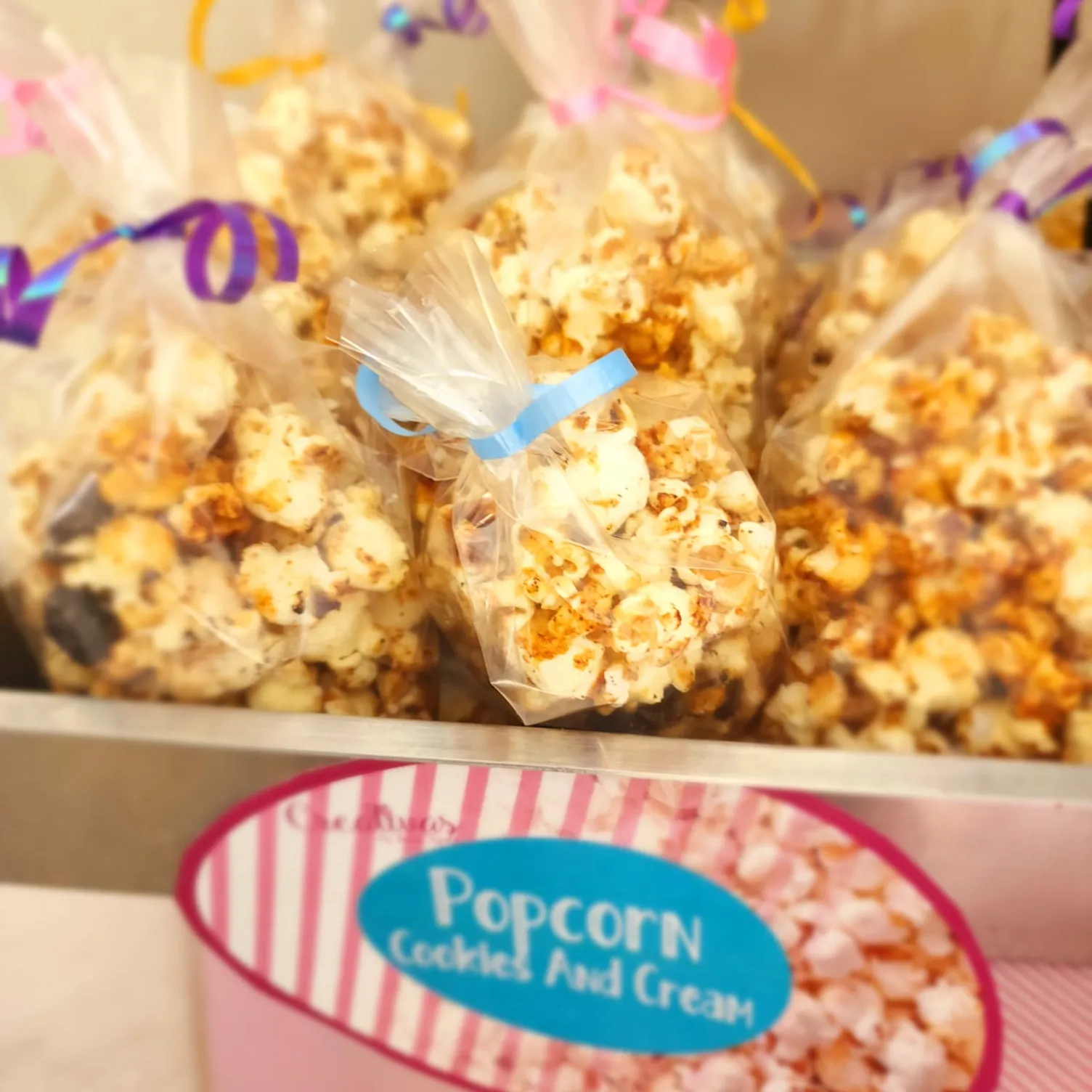 Presentación de palomitas de maíz gourmet en bolsas transparentes con listones, ideal para eventos.