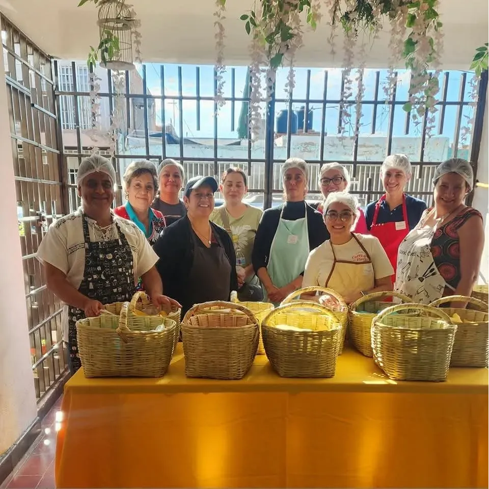 Grupo de mujeres sonrientes, en una clase de tacos de canasta, mostrando sus canastas.